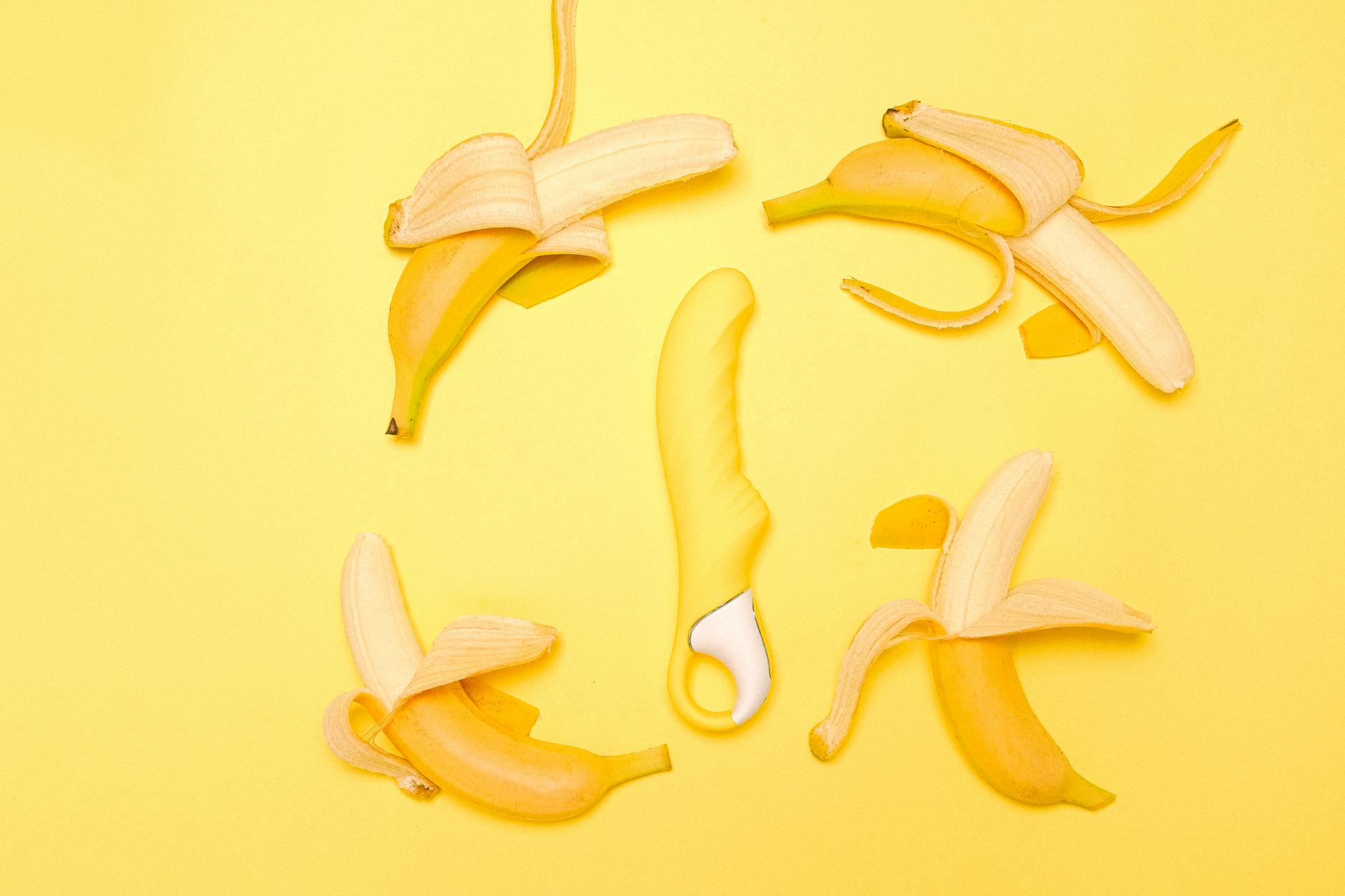 Yellow lemon-shaped clitoral vibrator on a bright yellow background surrounded by fresh lemons