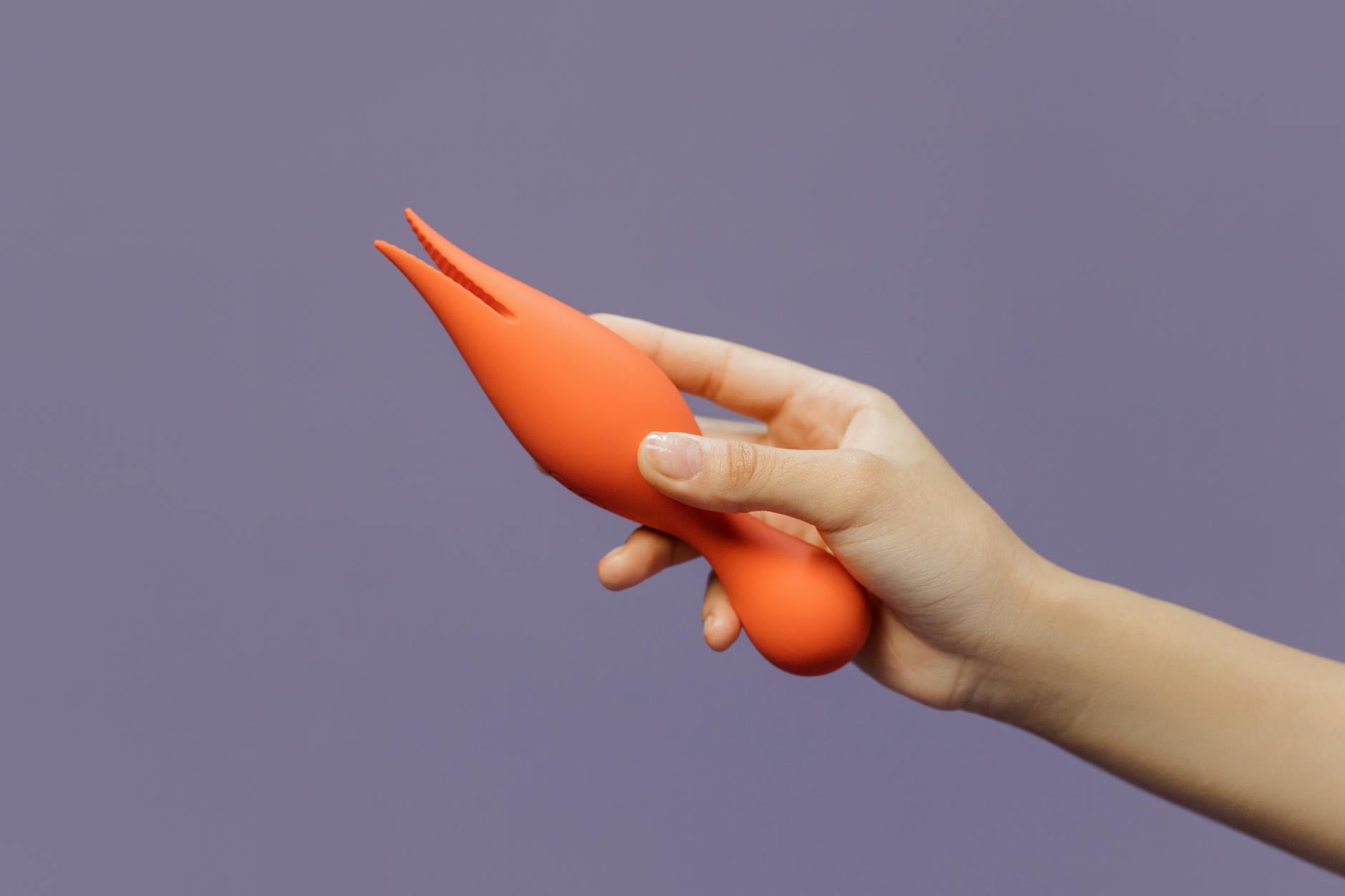 Hand holding a lemon-colored vibrator against a minimalist purple backdrop, symbolizing modern pleasure and intimacy.