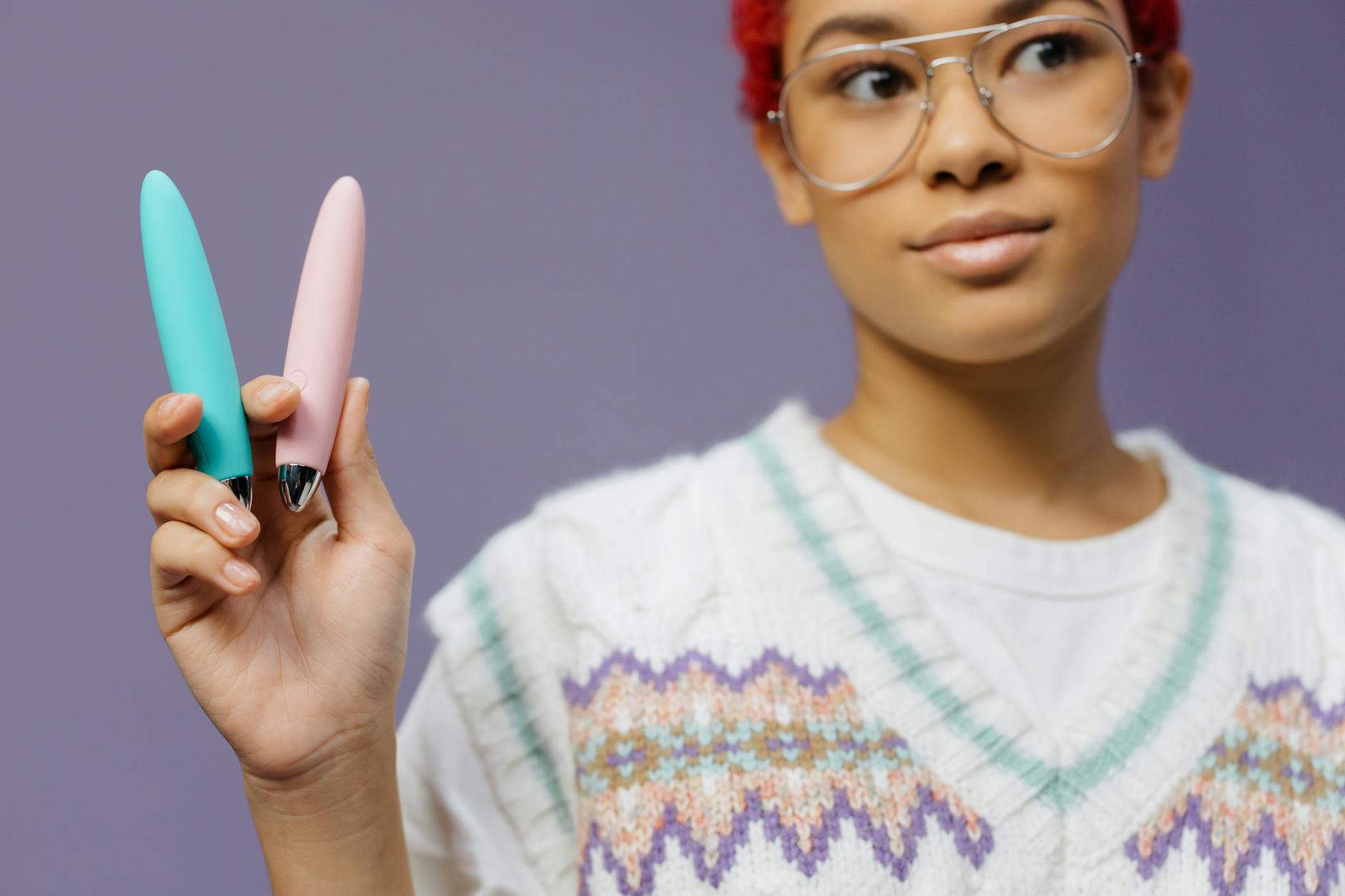 A woman holding two colorful vibrators against a purple background, representing discreet pleasure