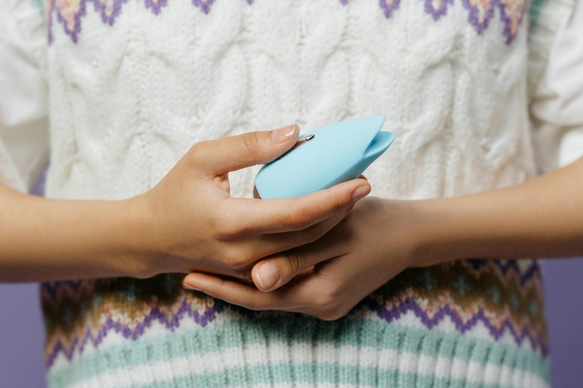 Hands holding a blue lemon vibrator against a knitted sweater, demonstrating comfort and ease of use